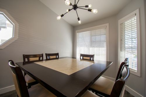 Free Elegant dining room featuring a modern chandelier and large windows for natural light. Stock Photo