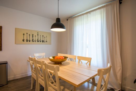 Cozy dining area with a wooden table, chairs, and modern decor accentuated by natural light.