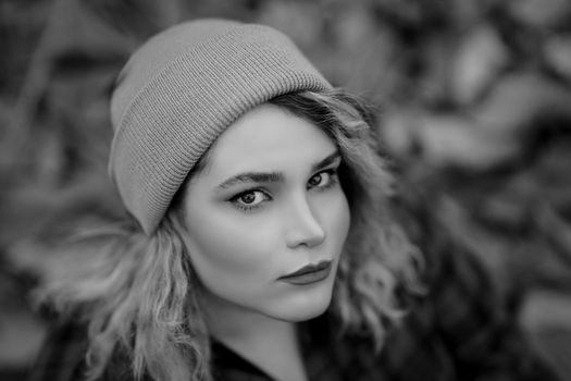 Close-up grayscale portrait of a woman wearing a beanie with selective focus.