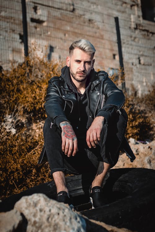 Free Man in Black Leather Jacket Sitting on a Tire Stock Photo