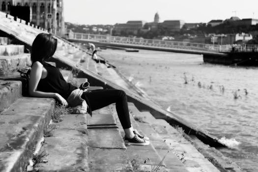 一张黑白照片中，一名女子躺在城区河边，捕捉到了宁静的时刻