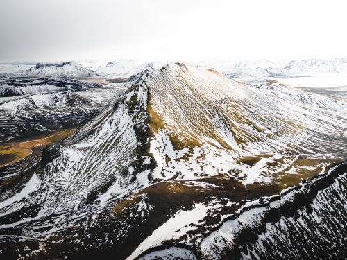 Free Stunning aerial view of a snow-capped mountain and rugged terrain, capturing the serene beauty of winter. Stock Photo