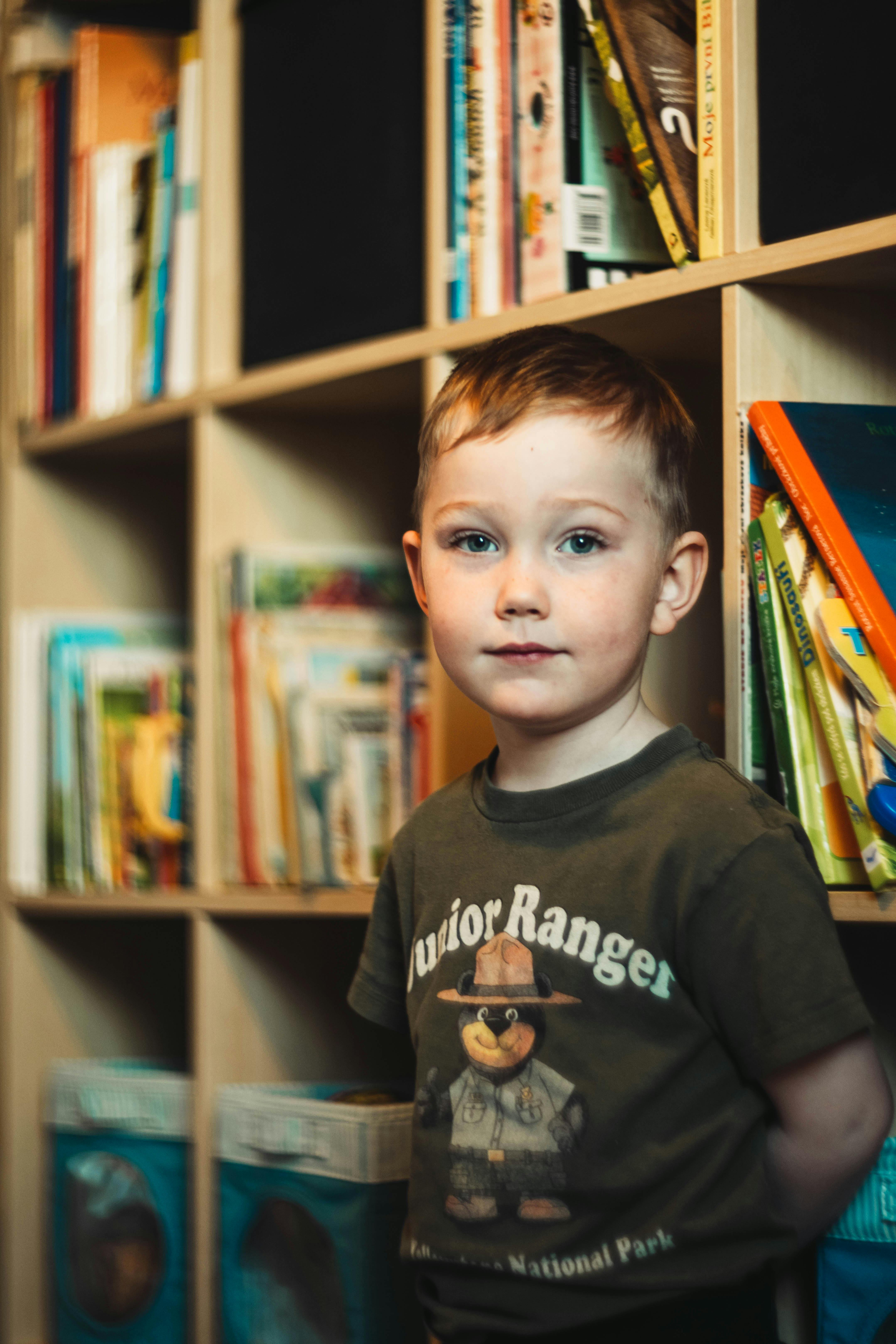 a boy standing in front of a bookcase