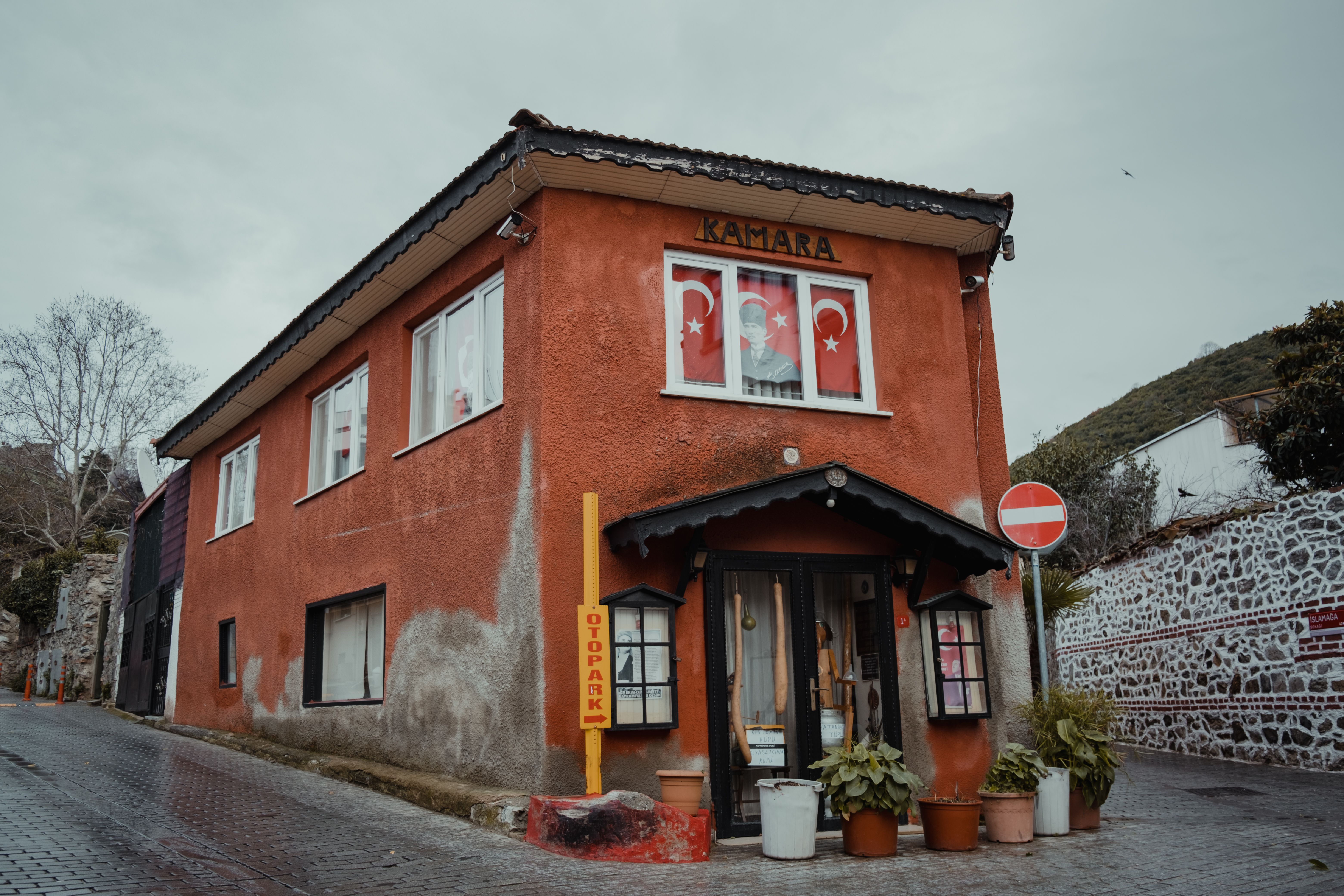 Charming red facade building displaying Turkish flags, set along a quaint urban street.