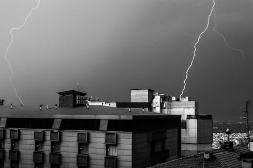 Grayscale Photo of Building with Lightning Stroke In The Night Sky