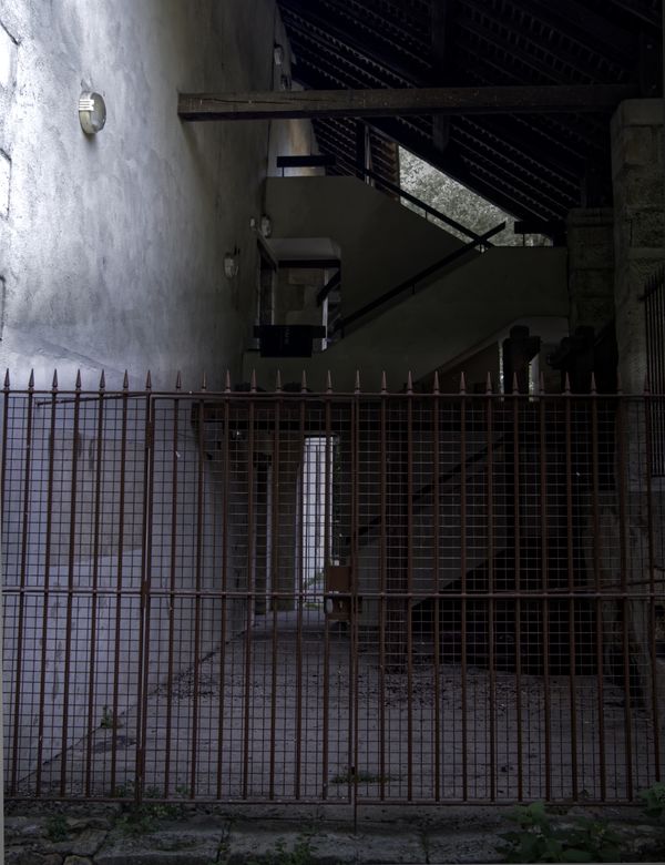 Grille de fer rouillée devant un bâtiment sombre à l'escalier de béton