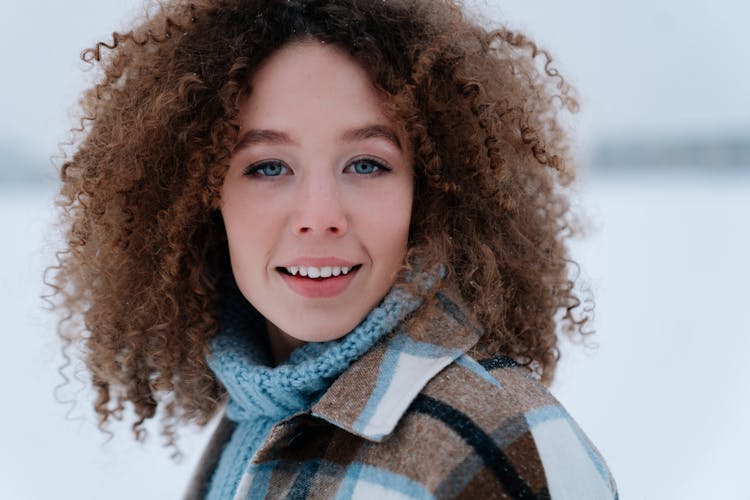 Portrait Of Woman With Curly Hair Wearing Winter Clothes Looking At Camera