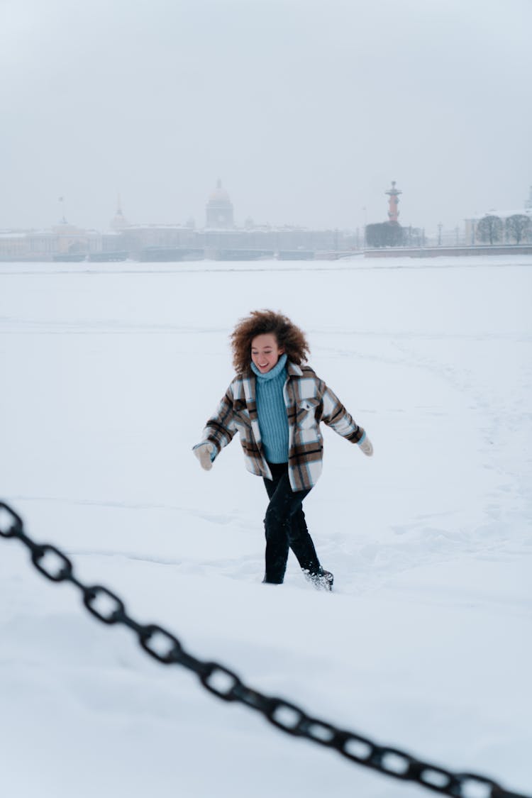 Woman With Curly Hair Wearing Winter Clothes Running Through Snow