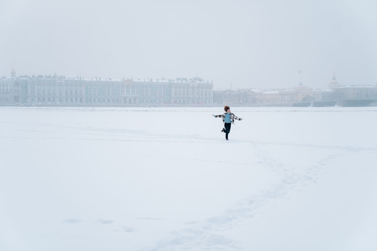 Lone runner on a vast frozen river with a city skyline behind