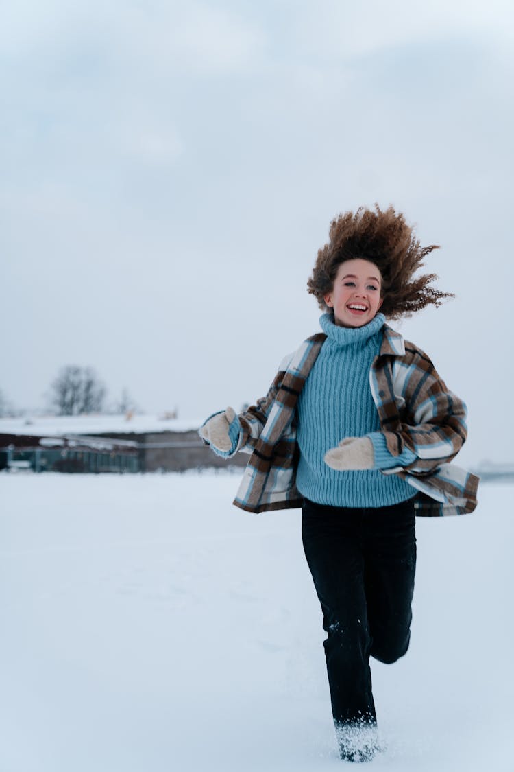 Happy Woman In Winter Clothes Running Through Snow Field