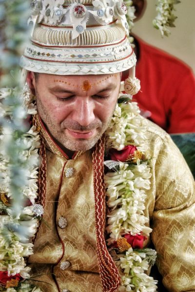 Groom in traditional attire with garlands