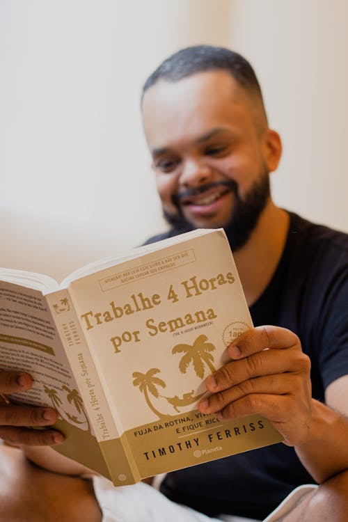 Free Bearded Man Smiling While Reading a Book Stock Photo