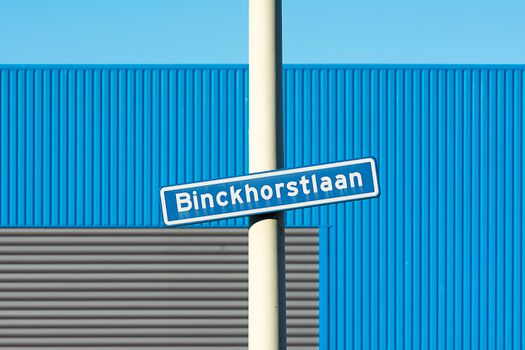 Street sign of Binckhorstlaan with blue and grey industrial building background.