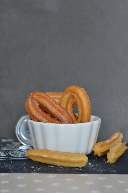 Free Churros in a Bowl and on a Black Surface Stock Photo