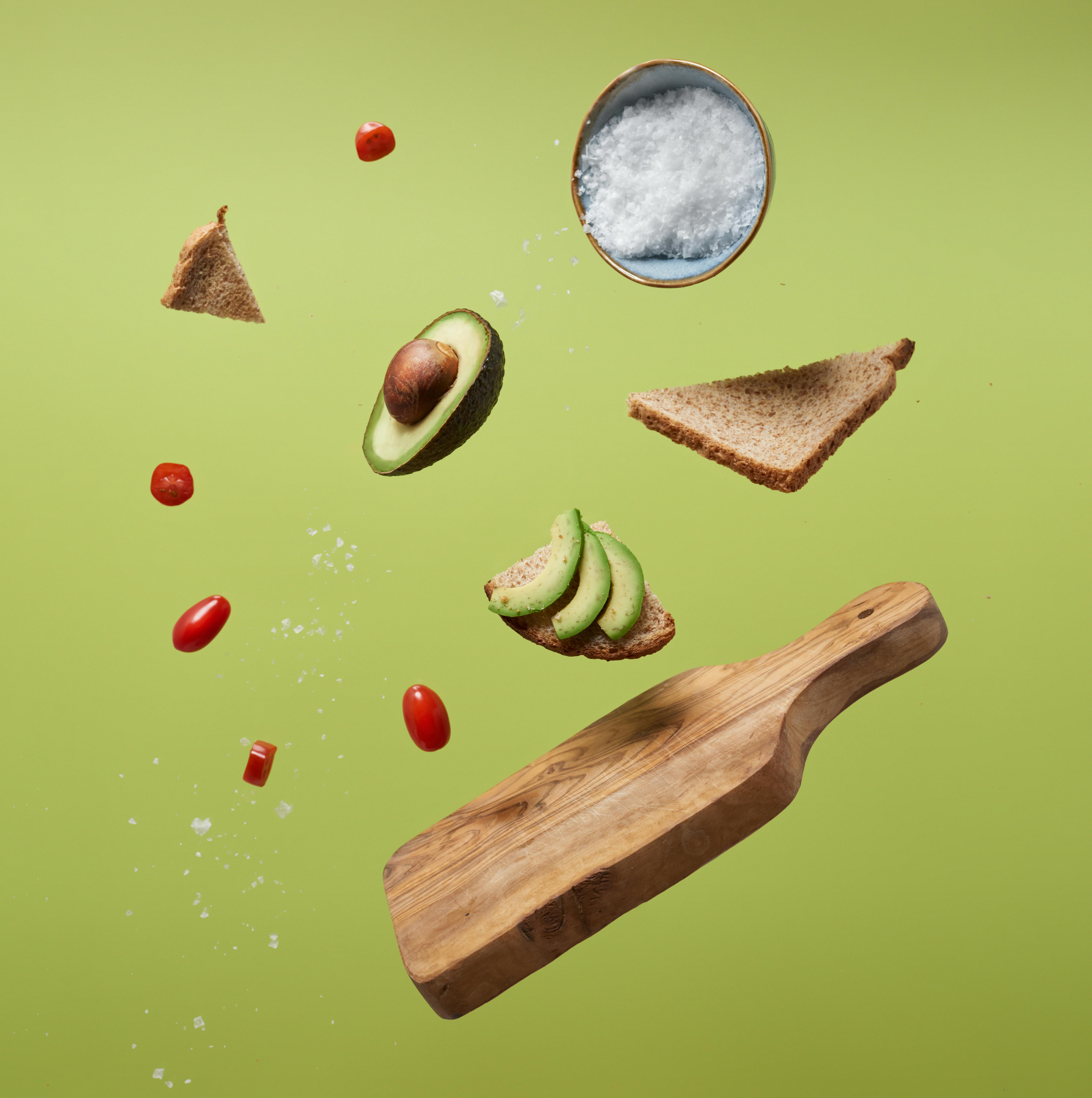 Floating avocado with bread and tomatoes creating a fresh food concept.