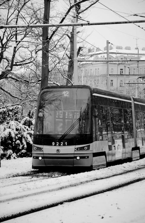 Grayscale Photo of a Tram Travelling on a Snow Covered Tramway