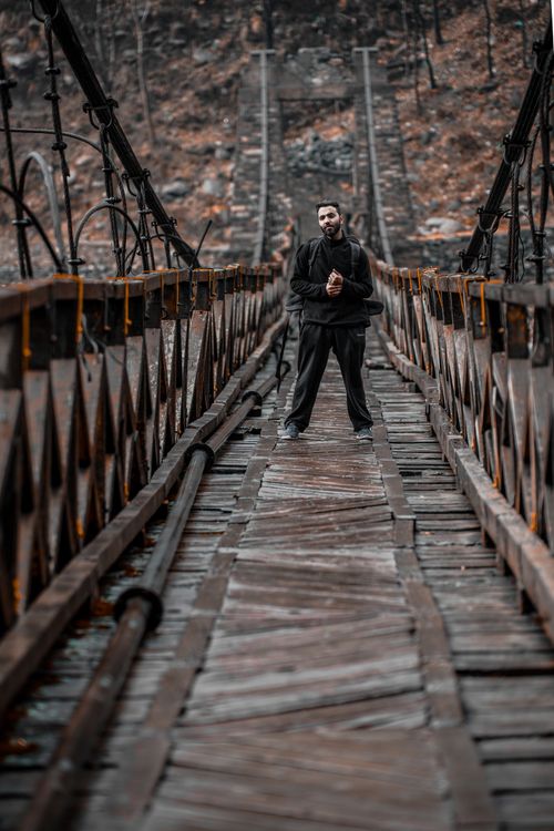 A Man in Black Clothing Standing on Wooden Foot Bridge · Free Stock Photo