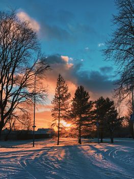 A stunning winter scene with a snowy road lined by trees at sunset in Estonia.