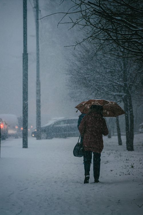 Free A person walks through a snowy street in Kaliningrad, Russia, under an umbrella. Stock Photo