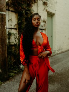 Attractive Woman in Long Red Dress Standing in Provocative Pose in Suburb Street