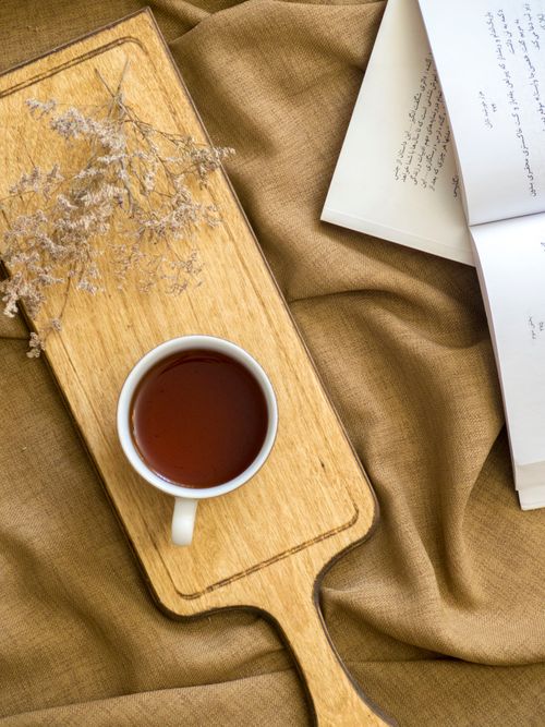 Free A warm setting with a cup of tea, open book, and dried flowers on a wooden board. Stock Photo