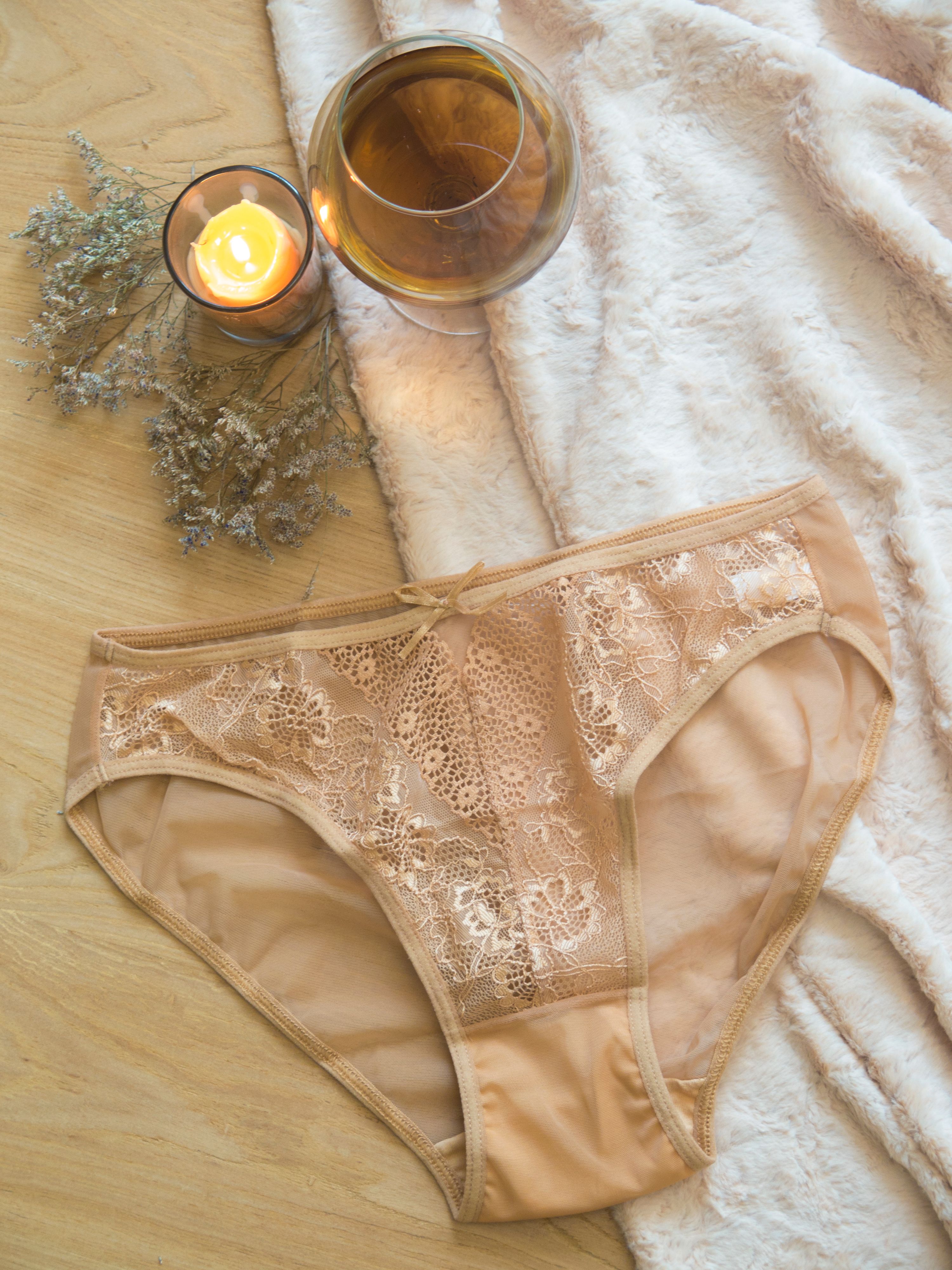 Sophisticated flatlay featuring lace lingerie, champagne, and warm candlelight for a cozy ambiance.
