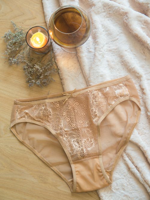 A Beige Panty Lying on a Wooden Surface with White Textile