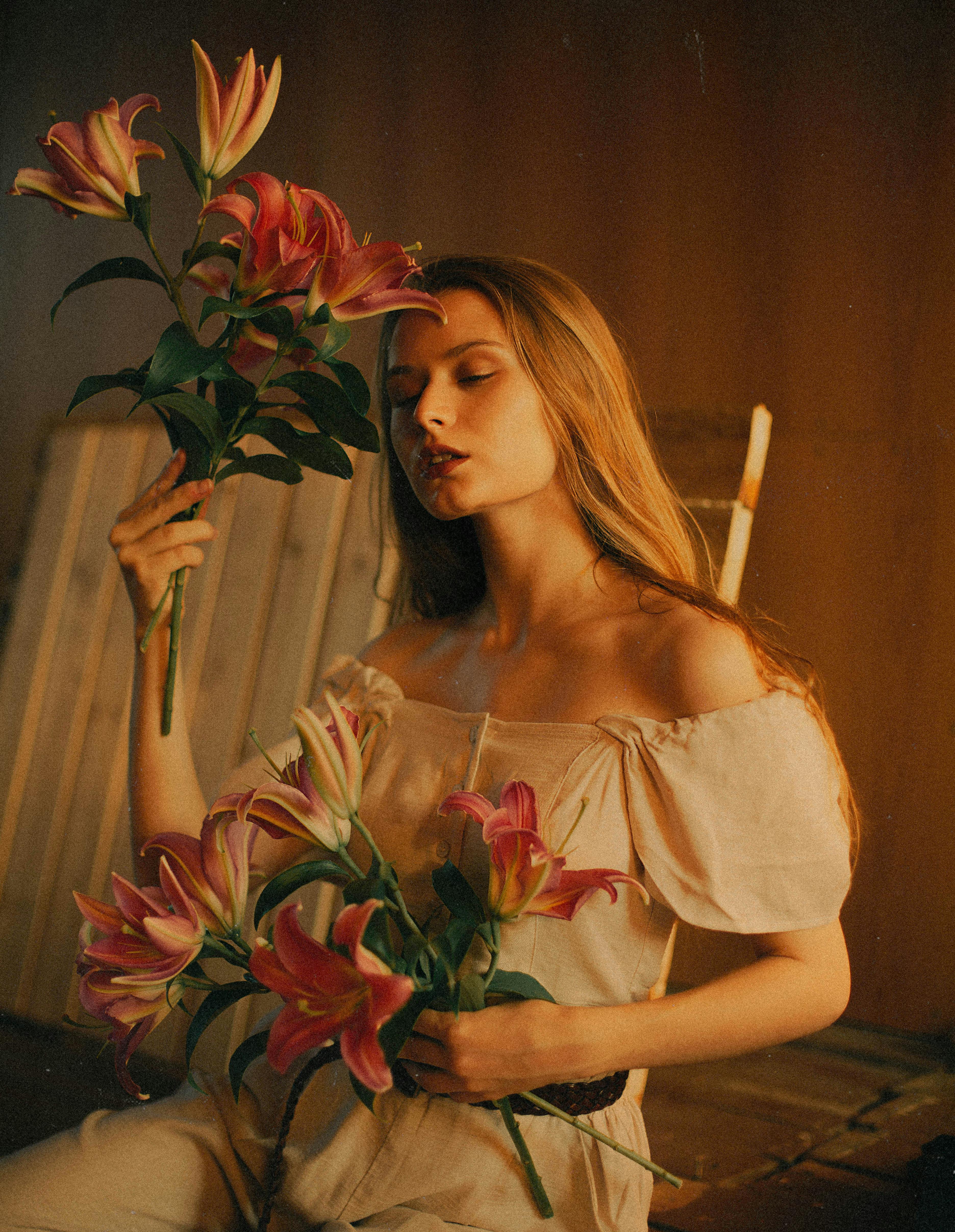Young woman in a studio holding lilies, captured with warm tones and summer vibes.