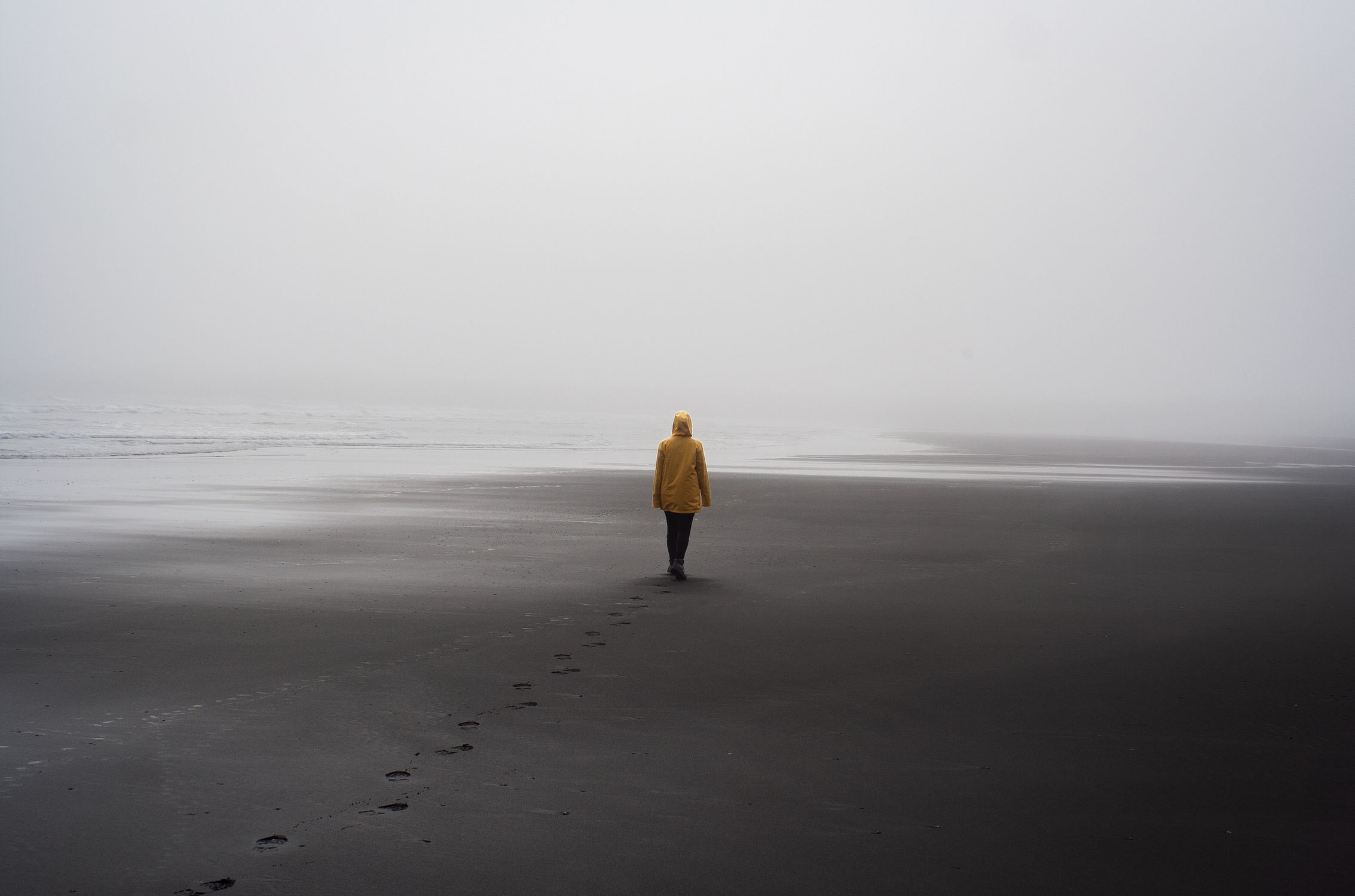 Person in Yellow Hoodie Standing on Beach · Free Stock Photo