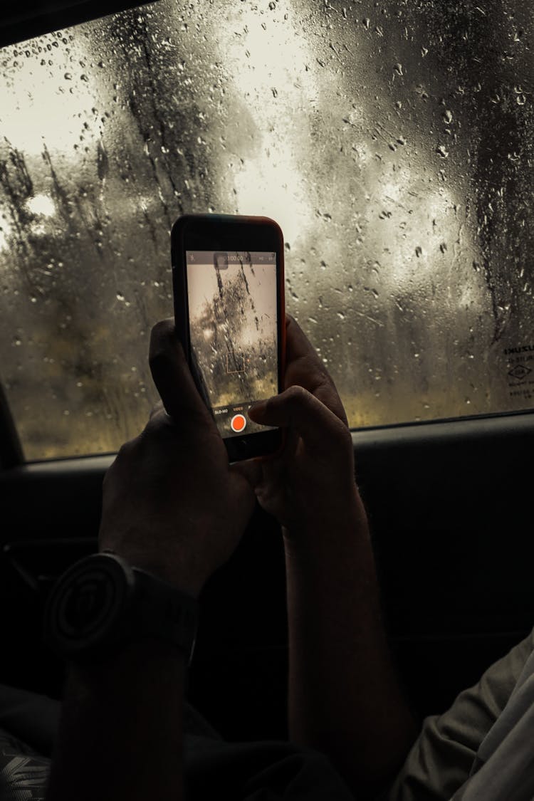 A Person Recording Rainfall Inside A Vehicle