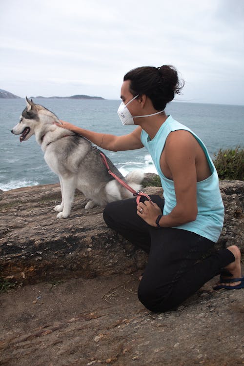 Man in Blue Tank Top Holding a Leash While Kneeling