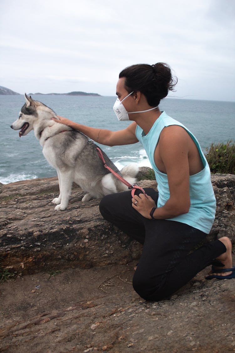 Man In Blue Tank Top Holding A Leash While Kneeling