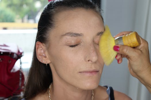 Close-up of a woman having makeup applied with a brush, emphasized focus on the face.