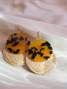 Close-up of handmade earrings with a unique design on a soft fabric background.