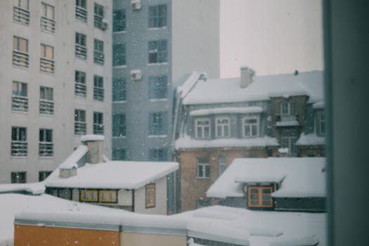 A serene view of city buildings covered in fresh snow, creating a classic winter atmosphere.