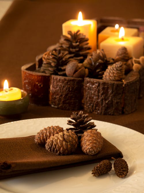 Brown Pine Cone Beside Yellow Candles