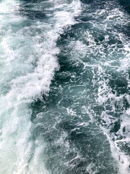 Vibrant turquoise ocean waves with splashing white foam, captured in a dynamic vertical frame.