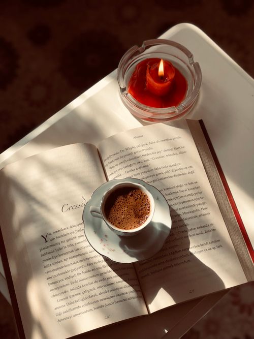 Free Warm scene of an open book with coffee and candlelight, perfect for relaxation. Stock Photo