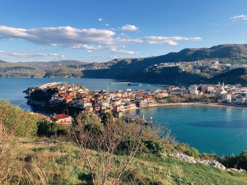 Free A picturesque seaside town surrounded by lush hills and blue waters on a sunny day. Stock Photo