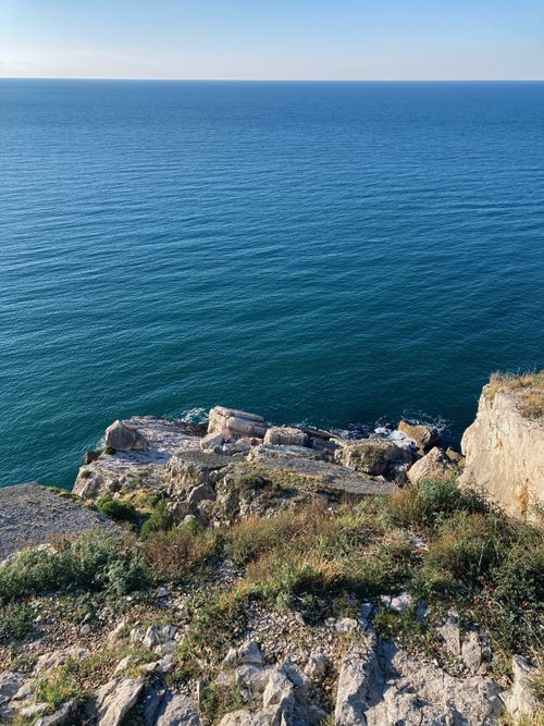 Free Stunning view of the ocean from a rocky cliff under a clear blue sky. Stock Photo