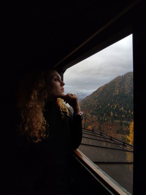 Free A woman looks out a window, admiring the autumn foliage of Scurelle, Italy. Stock Photo
