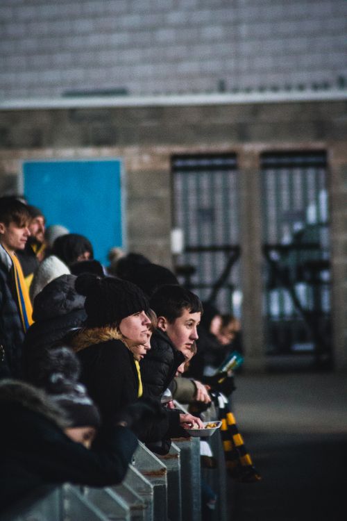 Free A diverse group of spectators, dressed warmly, watching a sporting event indoors. Stock Photo