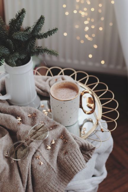 Warm and inviting indoor setting with coffee, cozy sweater, and festive decor.