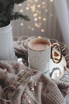 Warm and cozy autumn setup featuring a coffee mug, sweater, and fairy lights for a relaxing ambiance.