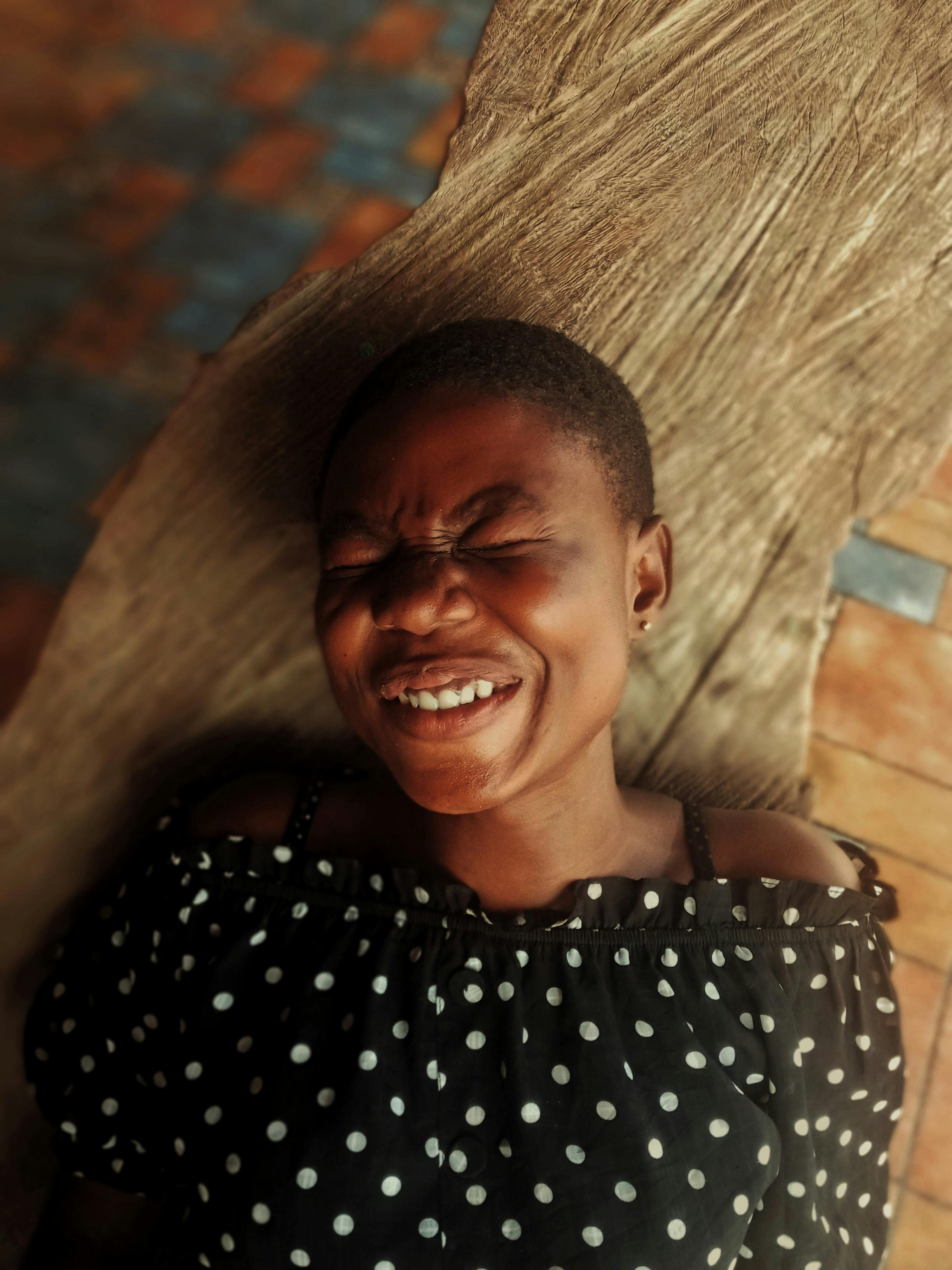 woman in polka dot shirt laughing with eyes closed