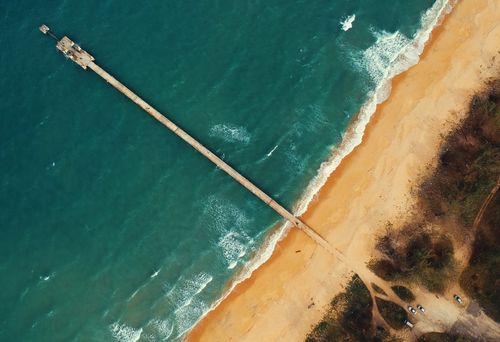 Free Aerial view of Kijal Beach, Terengganu's pier against clear turquoise waters. Stock Photo