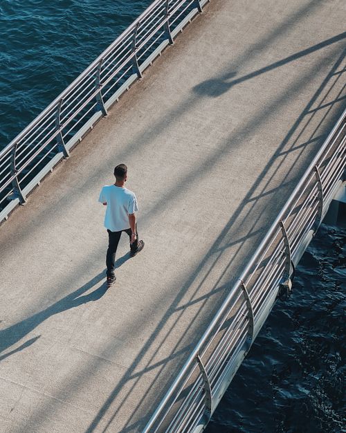 Free An aerial view of a man casually walking across a bridge overlooking the waterfront in sunny Istanbul. Stock Photo