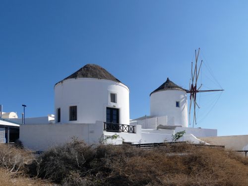 Free White windmill in Fira, Santorini against a clear blue sky, showcasing iconic Greek architecture. Stock Photo