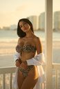 Attractive Suntanned Woman in Bikini with Seaside Resort in Background