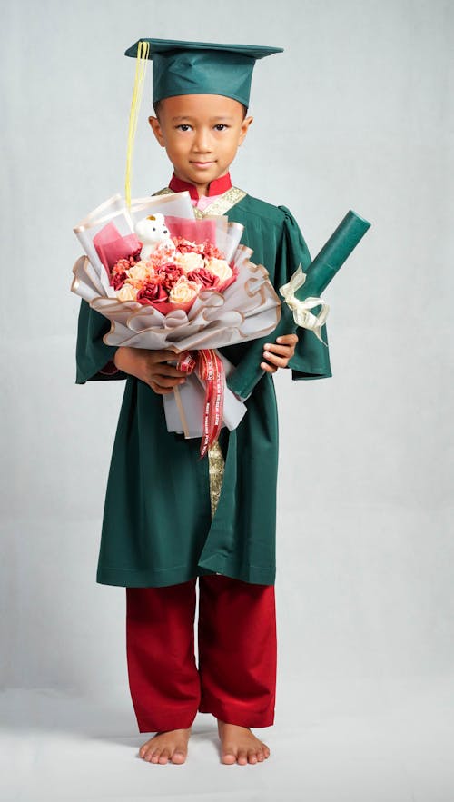 Boy Holding a Bouquet of Flowers and His Graduation Certificate